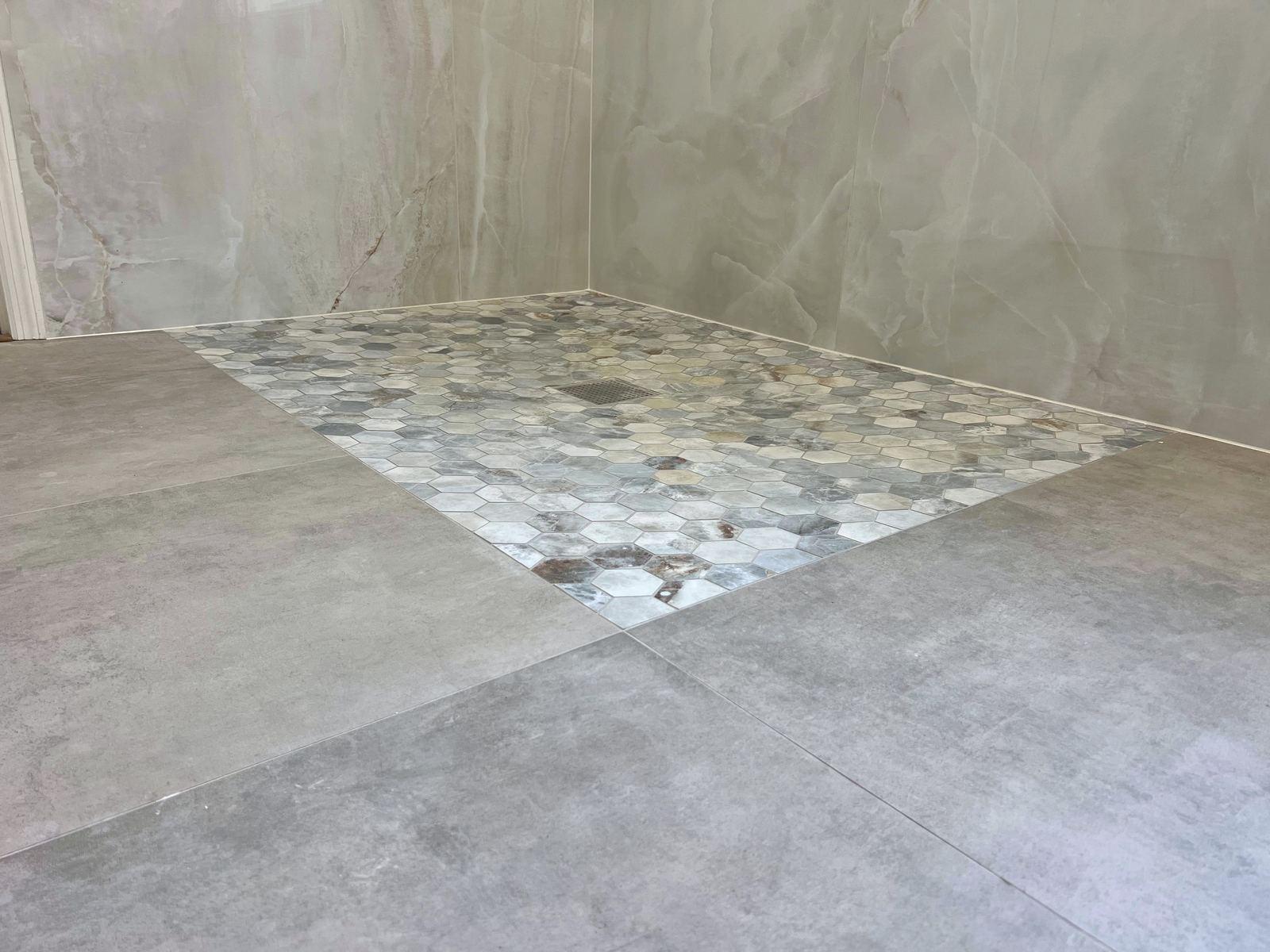 Large-format porcelain floor tile running flush into a tiled shower pan